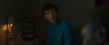 Movie still from “After Yang” (2021), directed by Kogonada – A man in a blue shirt is standing in a room; Close Up shot, Over the shoulder angle