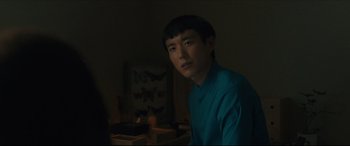 Movie still from “After Yang” (2021), directed by Kogonada – A man in a blue shirt is sitting in a room; Close Up shot, Over the shoulder angle