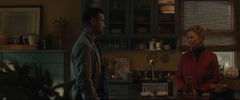 Movie still from “After Yang” (2021), directed by Kogonada – A man standing in a kitchen next to a sink; Medium shot, Over the shoulder angle