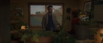 Movie still from “After Yang” (2021), directed by Kogonada – A man and a woman are standing in front of a window; Medium shot, Over the shoulder angle