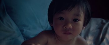 Movie still from “After Yang” (2021), directed by Kogonada – A young child laying on a bed looking at the camera; Extreme Close Up shot, High angle