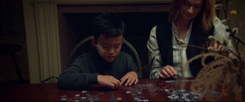 Movie still from “After Yang” (2021), directed by Kogonada – A young boy sitting at a table with a puzzle; Medium shot, High angle