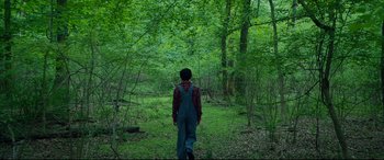 Movie still from “After Yang” (2021), directed by Kogonada – A man in overalls walking through the woods; Extreme Wide shot, High angle