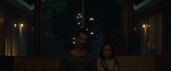 Movie still from “After Yang” (2021), directed by Kogonada – A man and a woman sitting on a couch; Medium shot, Over the shoulder angle