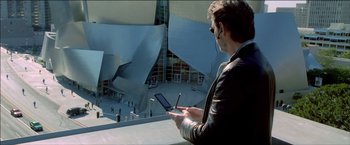 Movie still from “After the Sunset” (2004), directed by Brett Ratner – A man is looking at a tablet outside; Medium shot, High angle