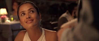 Movie still from “After the Sunset” (2004), directed by Brett Ratner – A woman smiling while a man takes a picture; Close Up shot, Over the shoulder angle