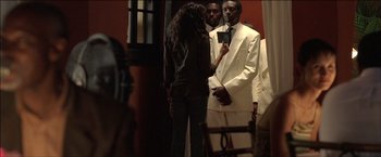 Movie still from “After the Sunset” (2004), directed by Brett Ratner – A group of people standing in a room; Medium shot, Over the shoulder angle