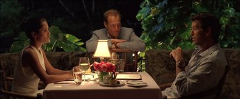 Movie still from “After the Sunset” (2004), directed by Brett Ratner – A man sitting at a table with a plate in front of him; Medium shot, Over the shoulder angle