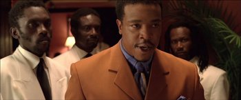 Movie still from “After the Sunset” (2004), directed by Brett Ratner – A man in a suit and tie standing next to another man; Close Up shot, Low angle