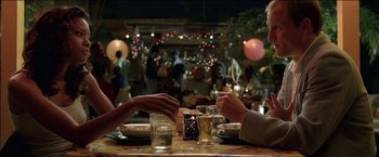 Movie still from “After the Sunset” (2004), directed by Brett Ratner – Two people are sitting at a table with drinks; Medium shot, Over the shoulder angle