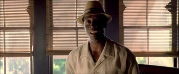 Movie still from “After the Sunset” (2004), directed by Brett Ratner – A man wearing a hat standing in front of a window; Close Up shot, Low angle