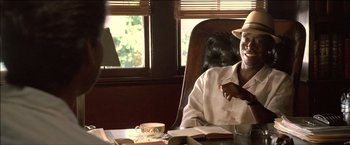 Movie still from “After the Sunset” (2004), directed by Brett Ratner – A man sitting at a table with a cup of coffee; Close Up shot, Over the shoulder angle