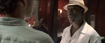 Movie still from “After the Sunset” (2004), directed by Brett Ratner – A man wearing a hat is looking at a man; Close Up shot, Over the shoulder angle