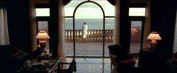 Movie still from “After the Sunset” (2004), directed by Brett Ratner – A woman in a white robe standing in front of a window; Wide shot, Low angle