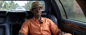 Movie still from “After the Sunset” (2004), directed by Brett Ratner – A man sitting in the back of a car wearing an orange shirt; Close Up shot, High angle