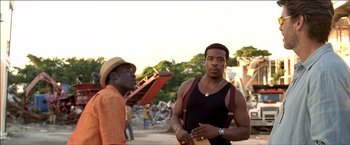 Movie still from “After the Sunset” (2004), directed by Brett Ratner – Two men standing next to each other on a dirt field; Medium shot, Low angle