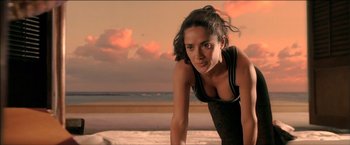 Movie still from “After the Sunset” (2004), directed by Brett Ratner – A beautiful woman in a black top standing in front of the ocean; Medium shot, Low angle