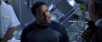 Movie still from “After the Sunset” (2004), directed by Brett Ratner – A man in a wetsuit standing in a room; Close Up shot, Over the shoulder angle