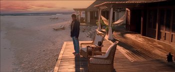 Movie still from “After the Sunset” (2004), directed by Brett Ratner – A man standing on a wooden deck near a beach; Wide shot, High angle