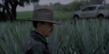 An older man wearing a cowboy hat in a field