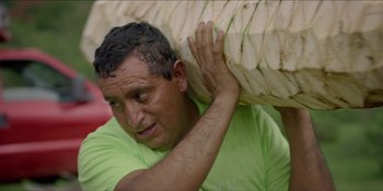 A man carrying a large piece of fruit on top of his head