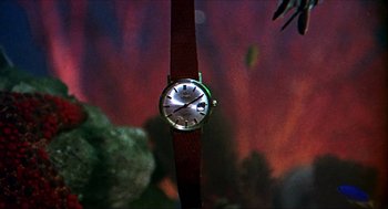 Movie still from “Age of Consent” (1969), directed by Michael Powell – A watch is hanging on the wall in front of a painting; Extreme Close Up shot, High angle