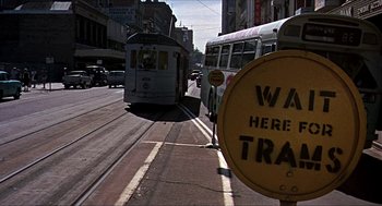 Movie still from “Age of Consent” (1969), directed by Michael Powell – A bus and a car driving down a street; Extreme Wide shot, Low angle