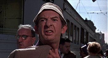 Movie still from “Age of Consent” (1969), directed by Michael Powell – A person wearing a hat with a train in the background; Close Up shot, Over the shoulder angle