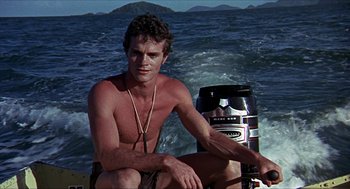 Movie still from “Age of Consent” (1969), directed by Michael Powell – A man sitting on the back of a boat in the ocean; Medium shot, Low angle