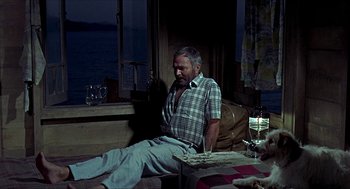 Movie still from “Age of Consent” (1969), directed by Michael Powell – An older man sitting on a couch next to a window; Medium shot, High angle