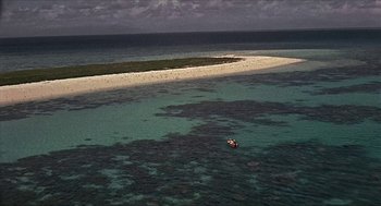 Movie still from “Age of Consent” (1969), directed by Michael Powell – An aerial view of an ocean with a boat floating on it; Extreme Wide shot, High angle