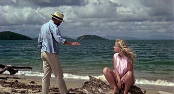 Movie still from “Age of Consent” (1969), directed by Michael Powell – A man and a woman on the beach by the water; Wide shot, Over the shoulder angle