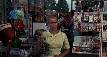 Movie still from “Age of Consent” (1969), directed by Michael Powell – A woman in a yellow dress holding a lobster in her hand; Medium shot, Over the shoulder angle