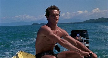 Movie still from “Age of Consent” (1969), directed by Michael Powell – A man sitting on a boat in the water; Medium shot, Low angle