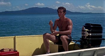 Movie still from “Age of Consent” (1969), directed by Michael Powell – A man sitting in a boat on the water; Medium shot, Low angle
