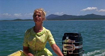 Movie still from “Age of Consent” (1969), directed by Michael Powell – A woman sitting on a boat next to a barrel; Medium shot, Low angle