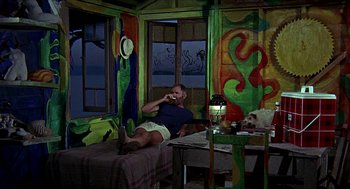 Movie still from “Age of Consent” (1969), directed by Michael Powell – A man sitting on a bed eating a sandwich; Wide shot, High angle