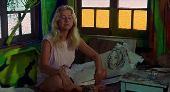 Movie still from “Age of Consent” (1969), directed by Michael Powell – A woman sitting on the ground painting a picture; Medium shot, Low angle