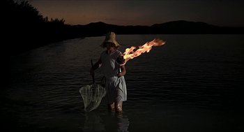 Movie still from “Age of Consent” (1969), directed by Michael Powell – A woman holding an umbrella in a body of water; Wide shot, High angle