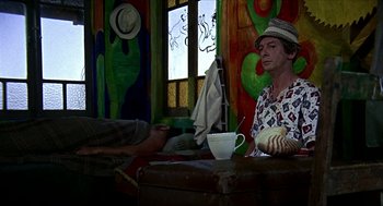 Movie still from “Age of Consent” (1969), directed by Michael Powell – A man sitting at a table with a cup of coffee; Medium shot, Low angle