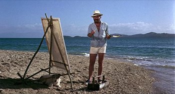 Movie still from “Age of Consent” (1969), directed by Michael Powell – A man standing in front of an easel on the beach; Wide shot, Low angle