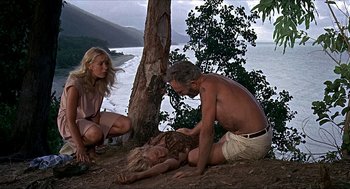 Movie still from “Age of Consent” (1969), directed by Michael Powell – Two women and a man on the ground near a tree; Wide shot, High angle