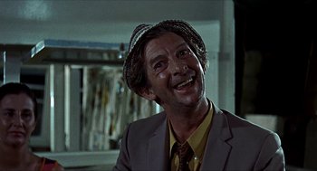 Movie still from “Age of Consent” (1969), directed by Michael Powell – A person wearing a suit and a hat; Close Up shot, Low angle