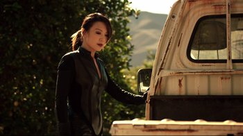 Movie still from “Agents of S.H.I.E.L.D.” (2013), created by Joss Whedon – A woman in a black leather jacket standing next to an old truck; Medium shot, Low angle