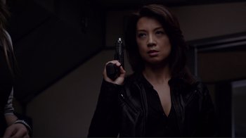 Movie still from “Agents of S.H.I.E.L.D.” (2013), created by Joss Whedon – A woman holding a gun while standing in a dark room; Close Up shot, Low angle