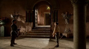 Movie still from “Game of Thrones” (2011), created by D.B. Weiss – A young boy standing in front of an archway; Wide shot, Low angle