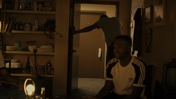Movie still from “Snowfall” (2017), directed by Hiro Murai – A man standing next to another man in a room; Medium shot, Over the shoulder angle