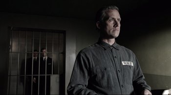 Movie still from “Agents of S.H.I.E.L.D.” (2013), created by Joss Whedon – A man standing next to a jail cell; Medium shot, Over the shoulder angle