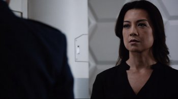 Movie still from “Agents of S.H.I.E.L.D.” (2013), created by Joss Whedon – A woman standing in front of a mirror in front of a wall; Close Up shot, Over the shoulder angle