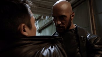 Movie still from “Agents of S.H.I.E.L.D.” (2013), created by Joss Whedon – A man with a shaved head and a leather jacket on; Close Up shot, Over the shoulder angle